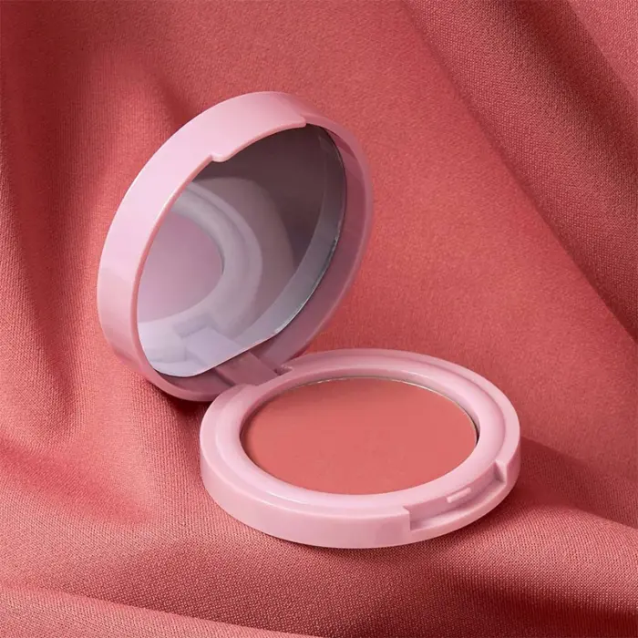 Close-up of a woman applying peach blush for a natural rosy glow.