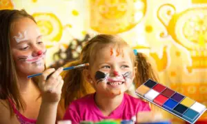 Professional face painter creating colorful designs on children's faces.